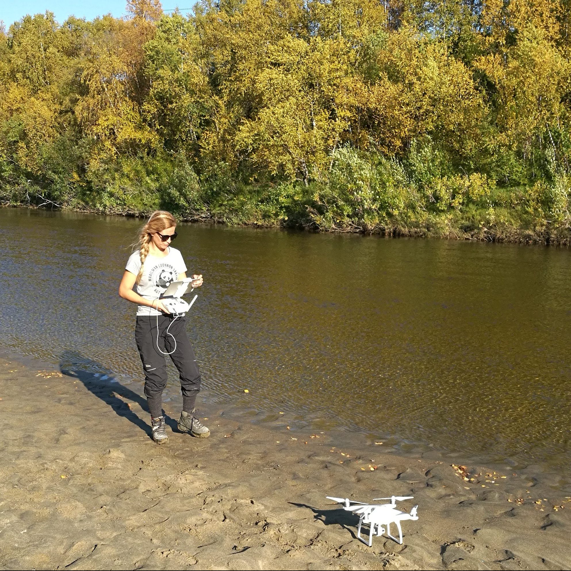 researcher operating a drone by a river
